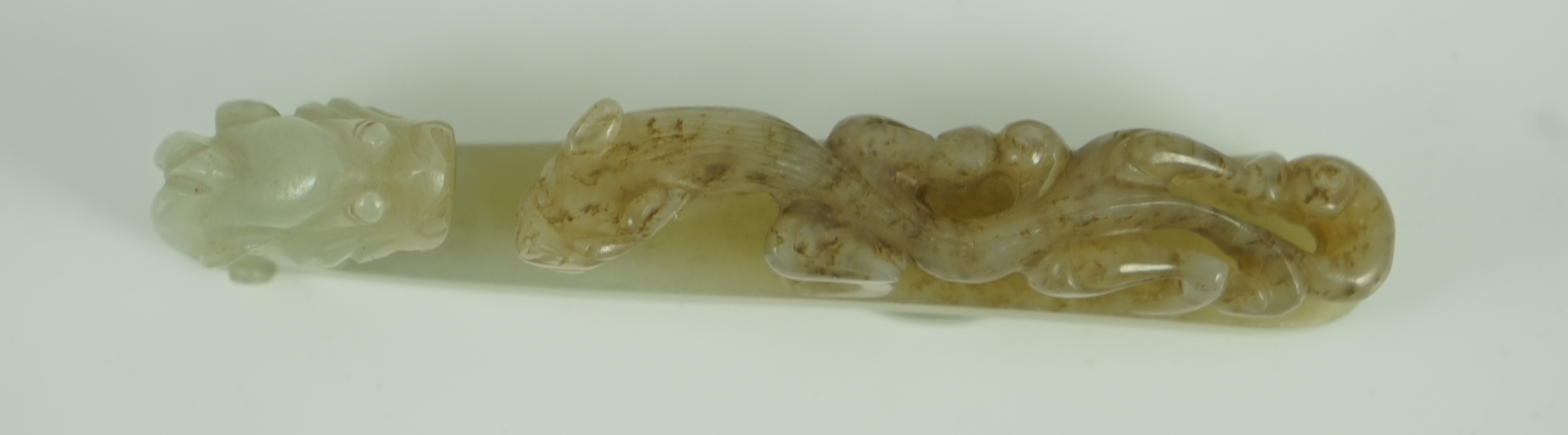 A Chinese pale celadon and brown jade ‘dragon’ belt hook, 18th/19th century 10.7 cm long